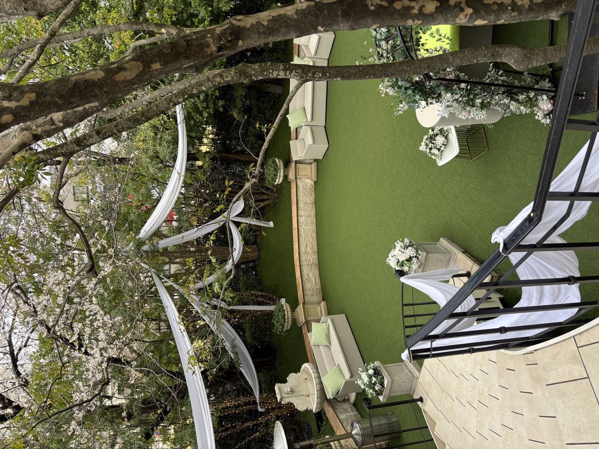 桜の咲く庭に白いドレープが張られ、ソファが並べられた中庭