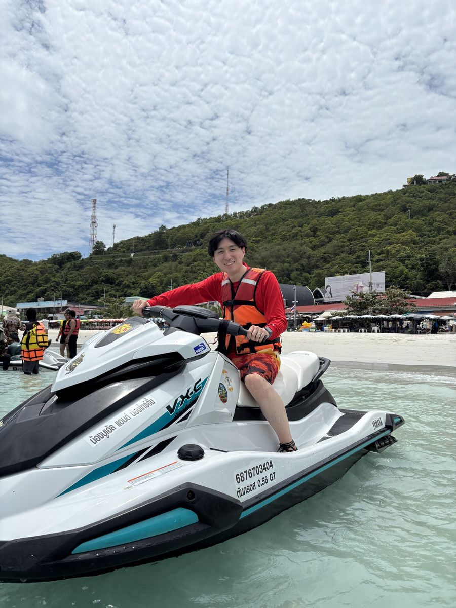 浅瀬のジェットスキーにまたがる、赤いライフジャケットの男性