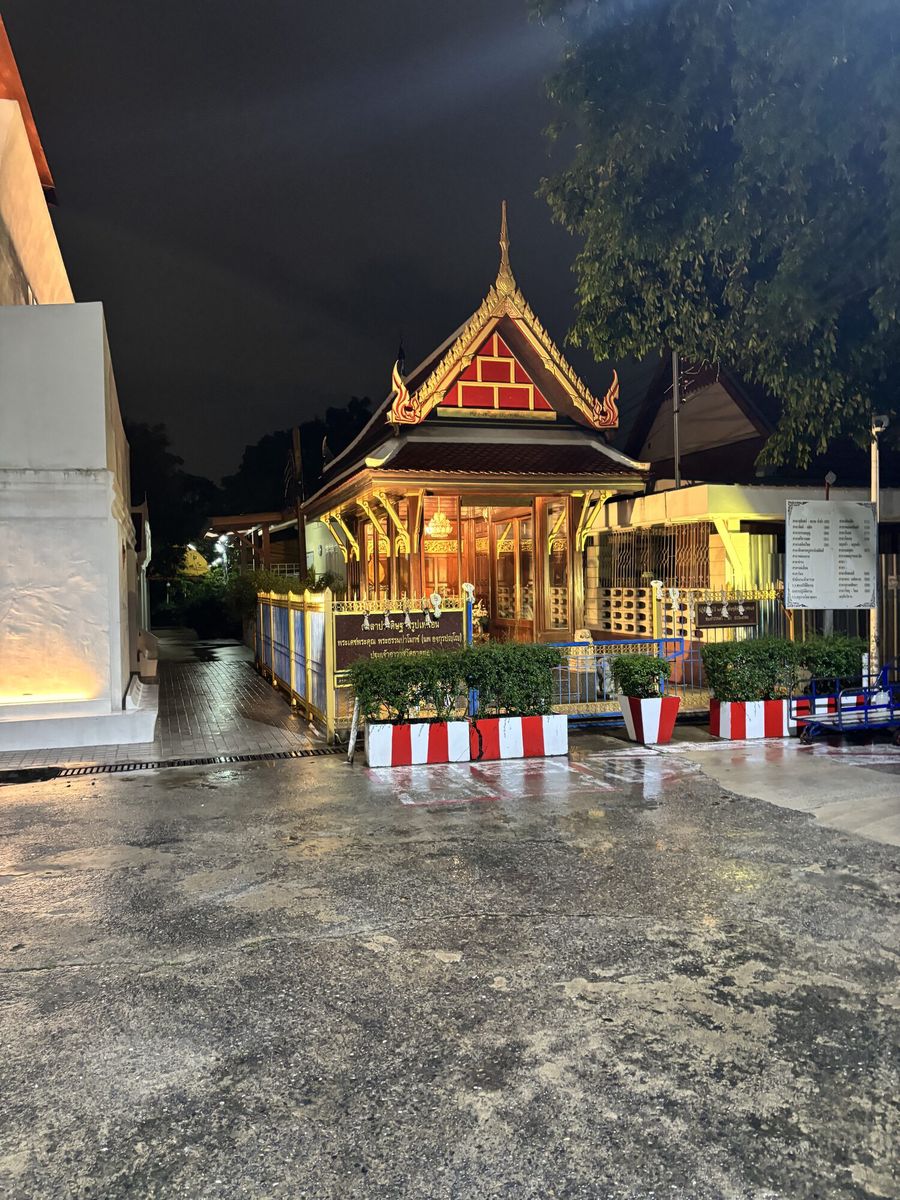 雨上がりの参道の先に、金色の灯りがともるタイ式の堂が建つ