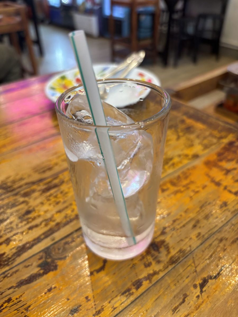 木のテーブルに置かれた、ストローの刺さった氷入りのグラス