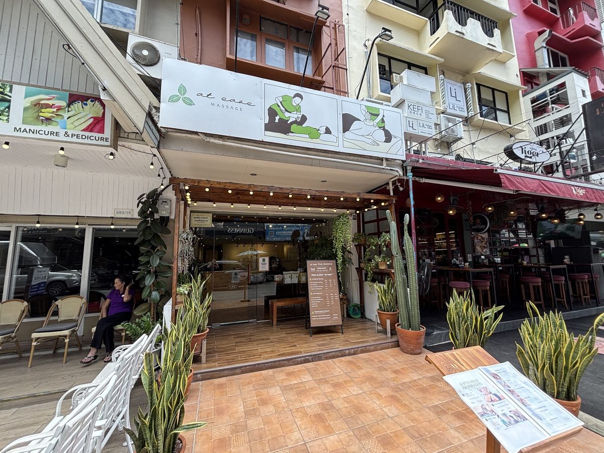 観葉植物とハンモックチェアを置いたカフェの店先。二階建ての建物が並ぶ