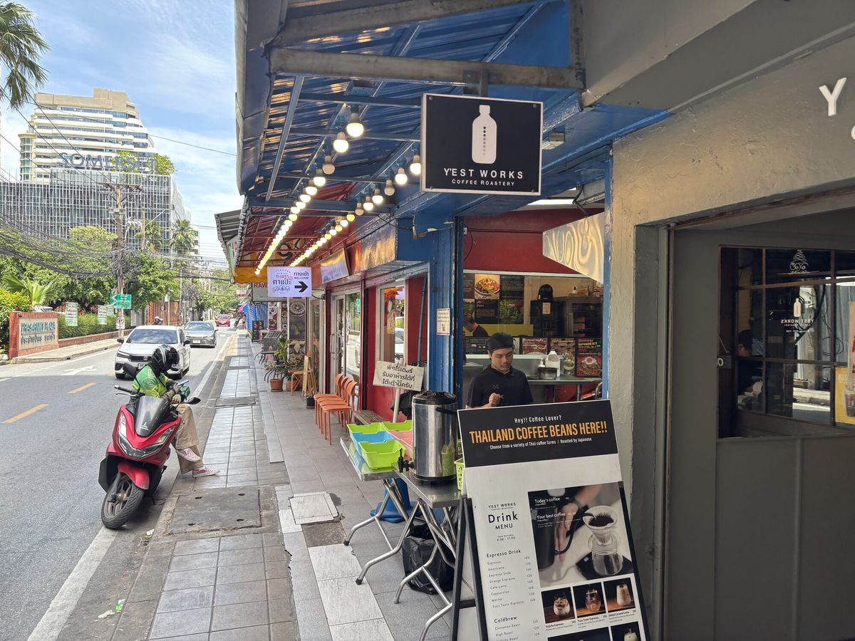 歩道沿いのコーヒー店。電球の連なる軒下にバイクが停まっている