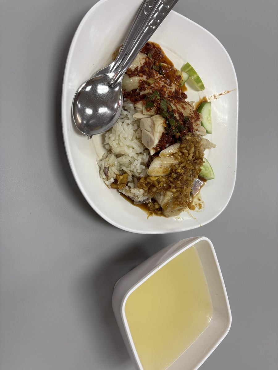 白い器のご飯に赤いタレがかかり、手前に小皿のスープが添えてある